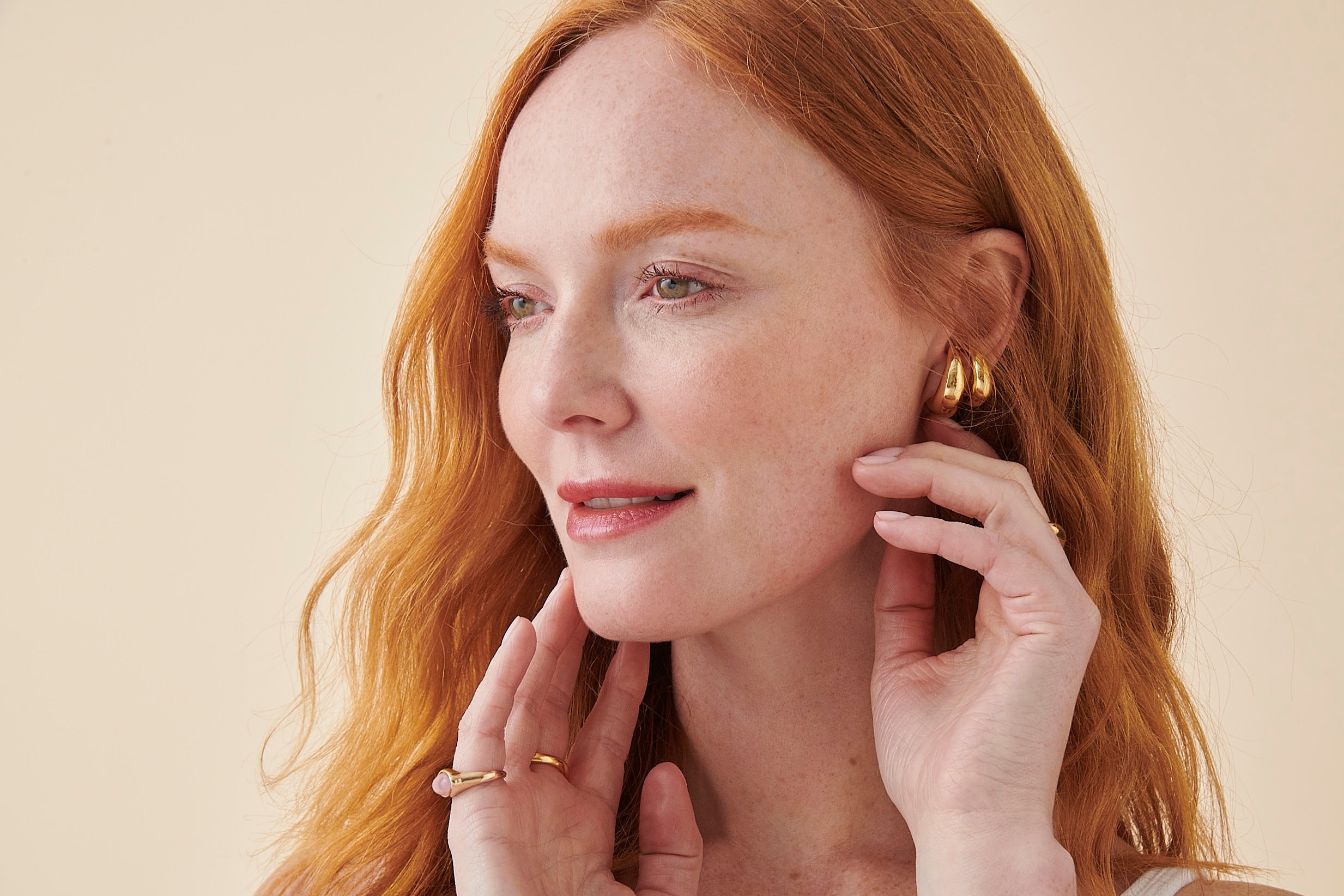 Close-up of woman's face, wearing gold jewellery and smiling