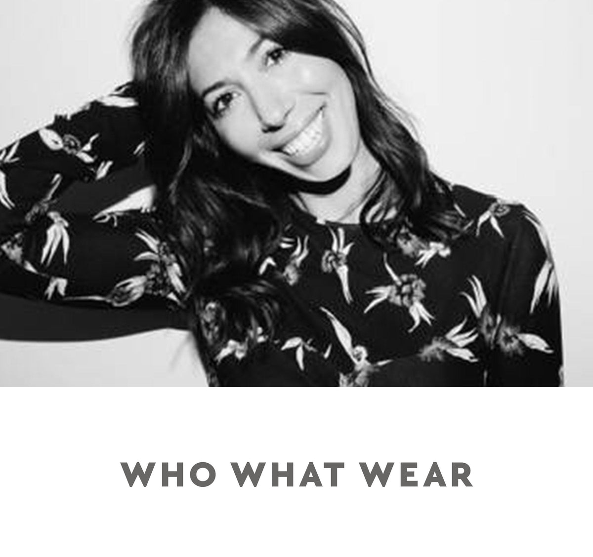 Black-and-white portrait of a smiling woman in a dark floral top, head tilted with hand behind her head; 'WHO WHAT WEAR'