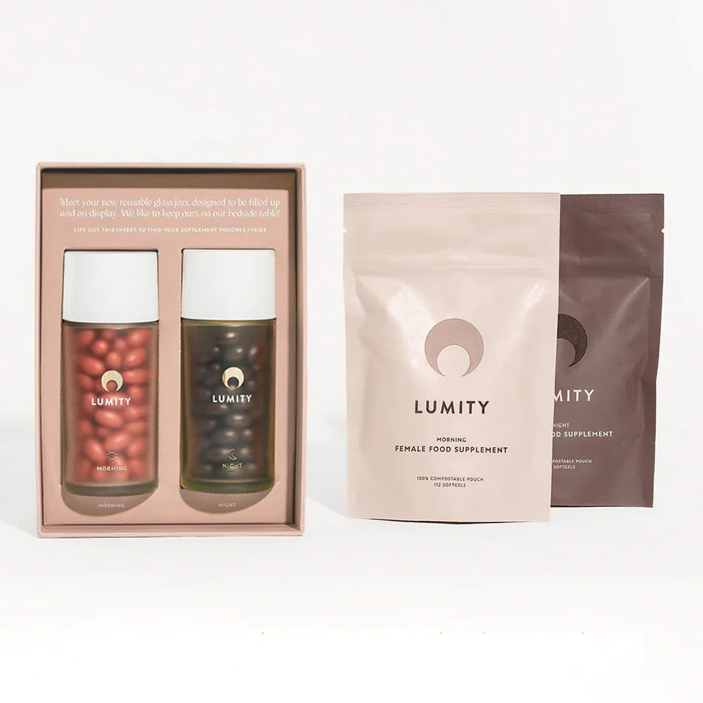 Lumity morning/night set — straight-on: two glass jars (white lids) with red MORNING/dark NIGHT capsules; beige/brown pouches