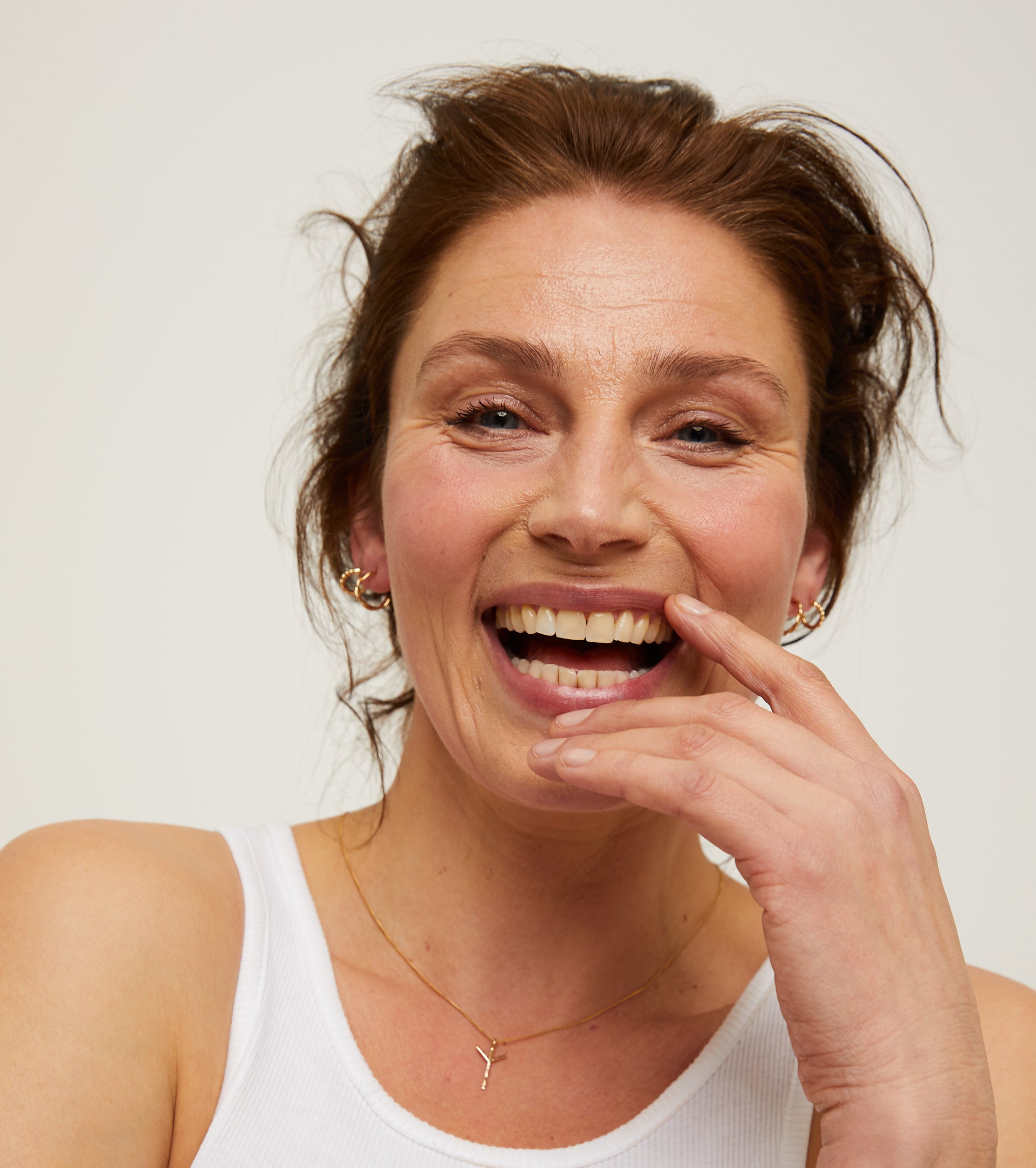 Woman smiling with fingers over mouth