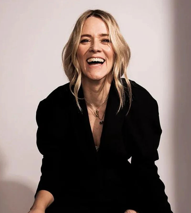 Woman smiling, wearing a black outfit on a plain background