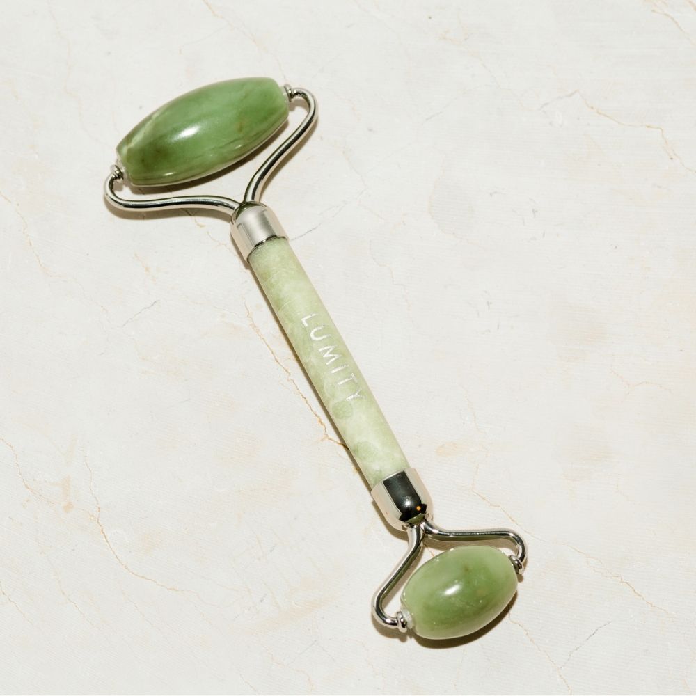Jade facial roller with 'Lumity' branding on a light marble background