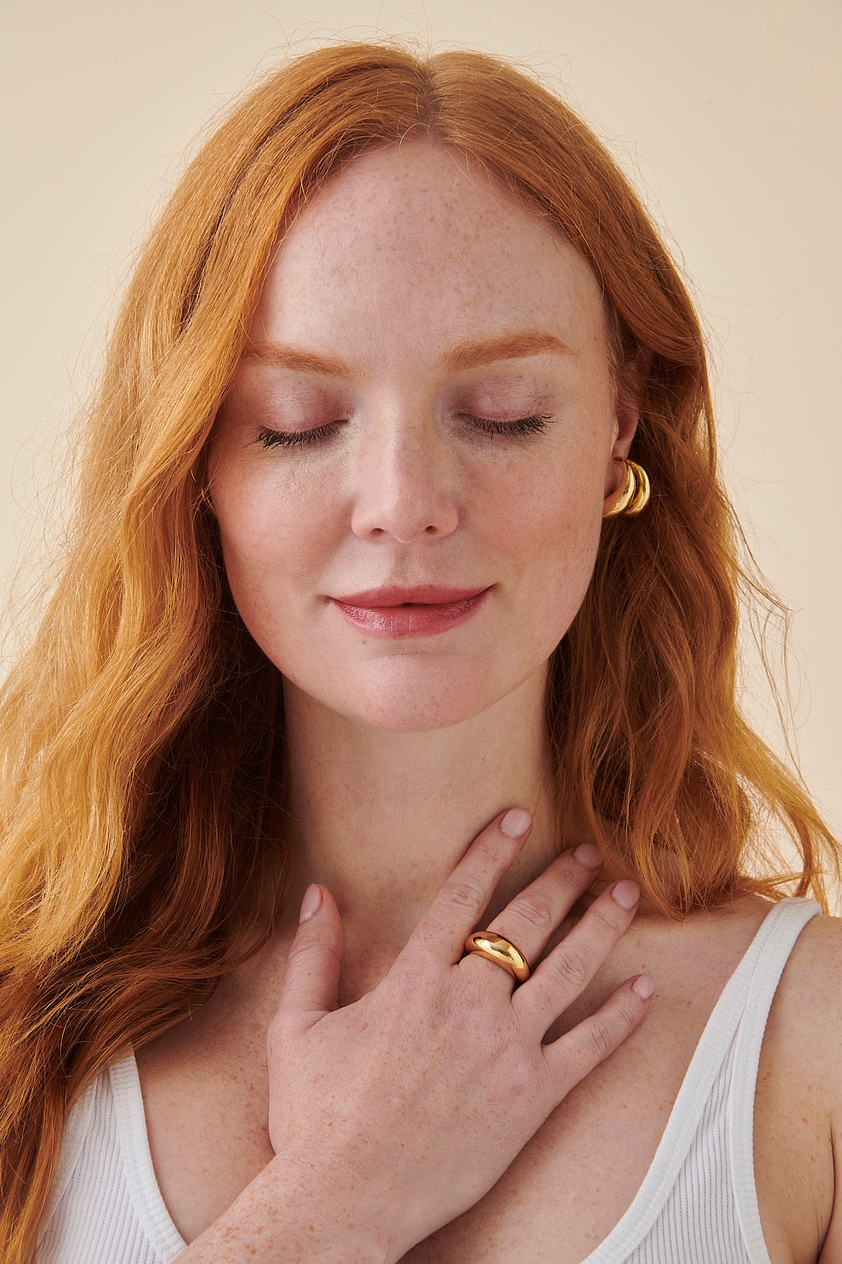 Photo of a woman smiling with her hand on her chest against plain background