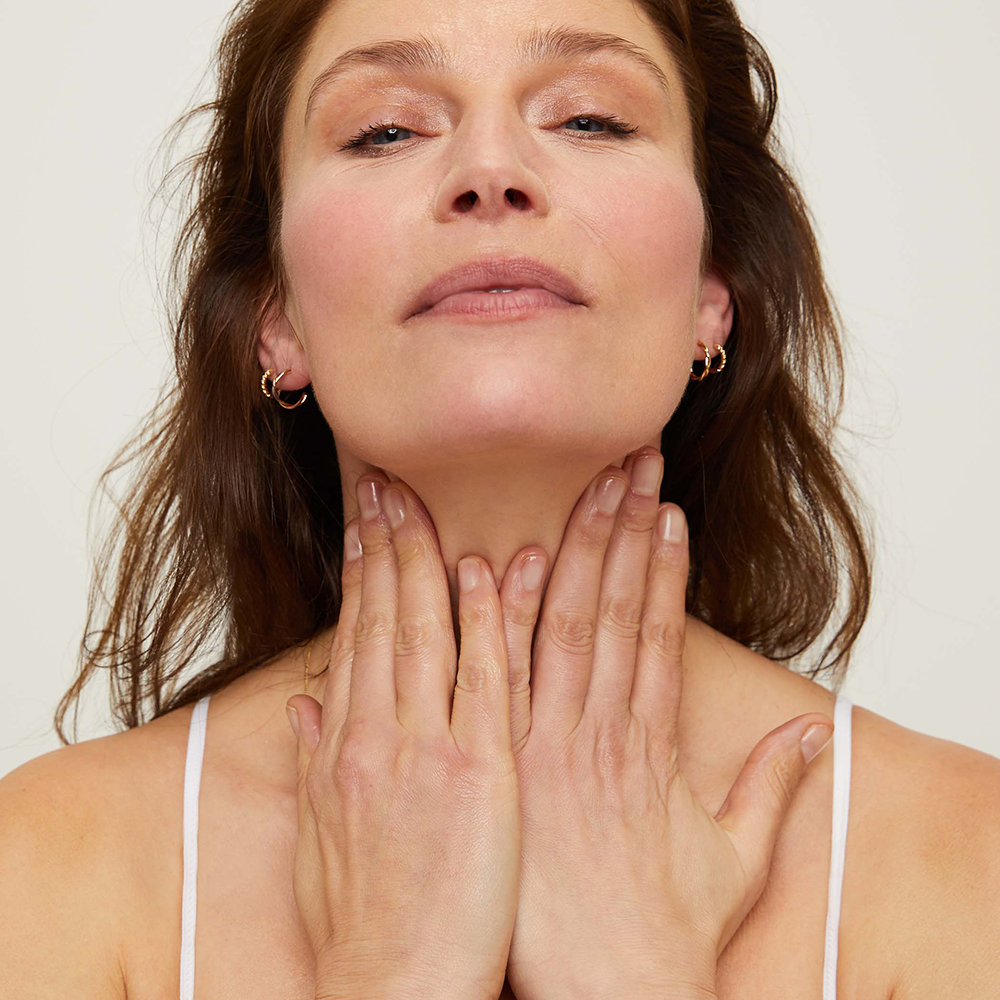 Woman with her neck and collar bone against a plain background