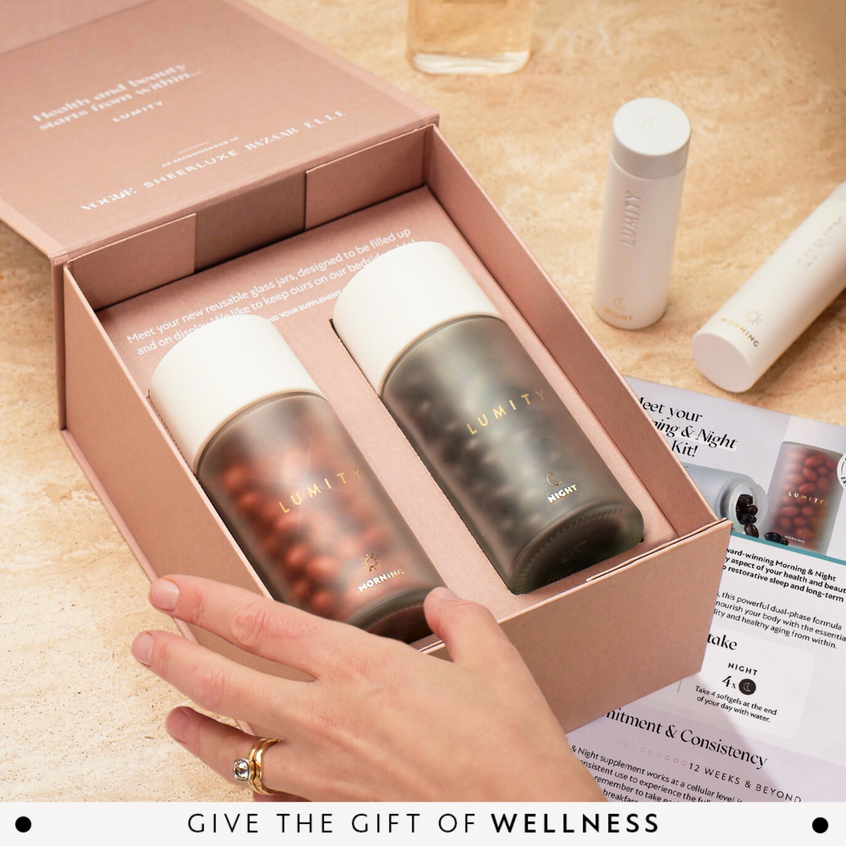 Opened gift box showing morning and night Lumity supplements with a hand reaching to pick one up