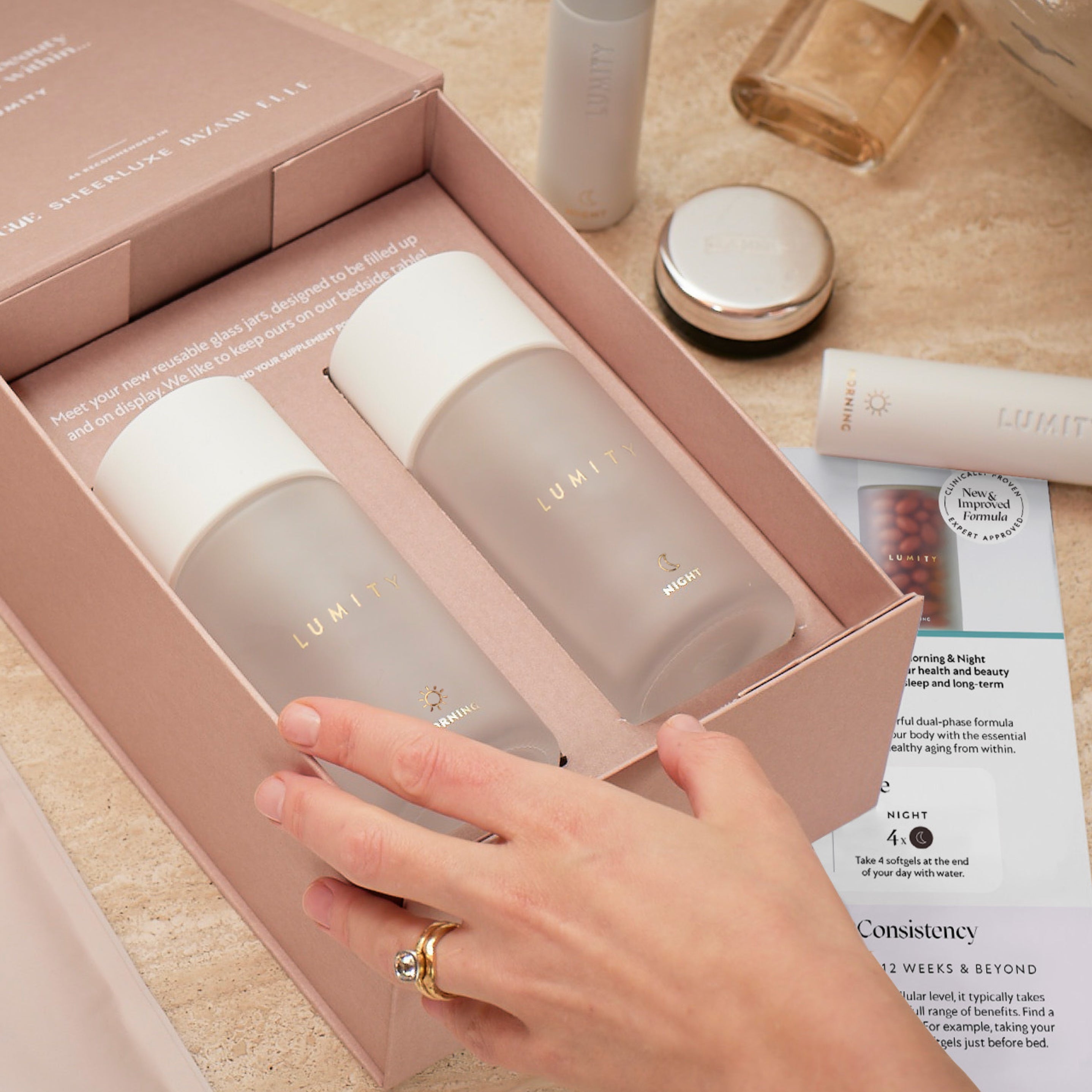 Person holding a pink box with two frosted bottles labeled morning and night for a skincare or supplement routine