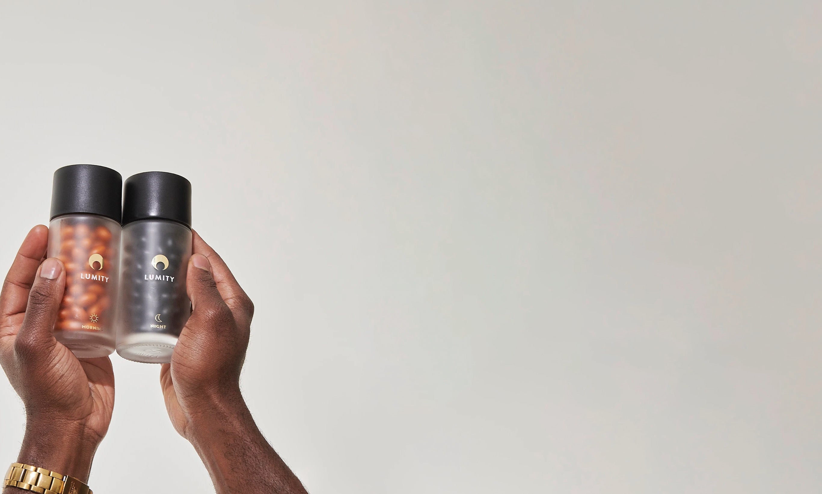 Morning & Night Male glass bottles with softgels inside held by a person against a white background