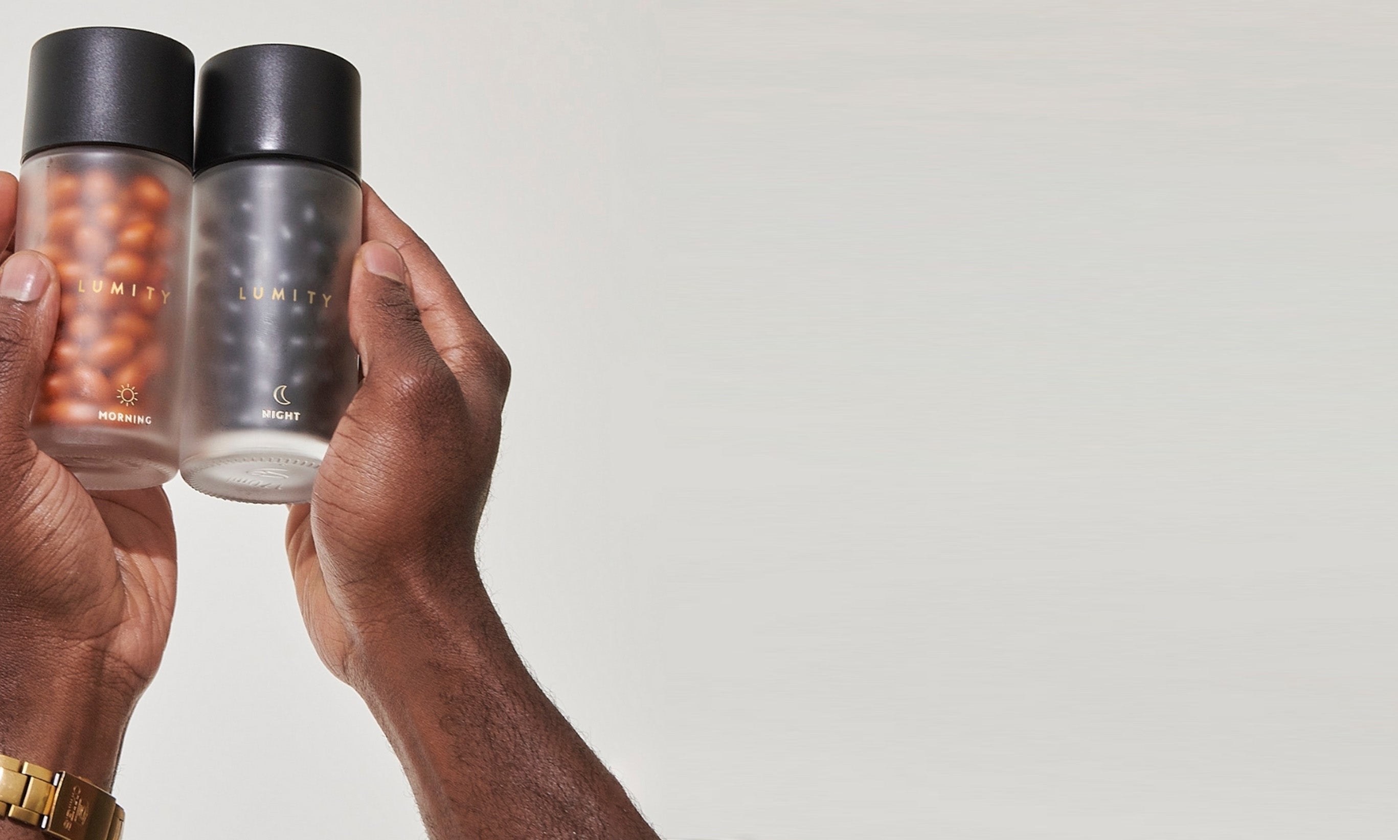 Morning & Night Male glass bottles with softgels inside held by a person against a white background