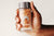Hand holding Lumity male morning supplements in glass jar