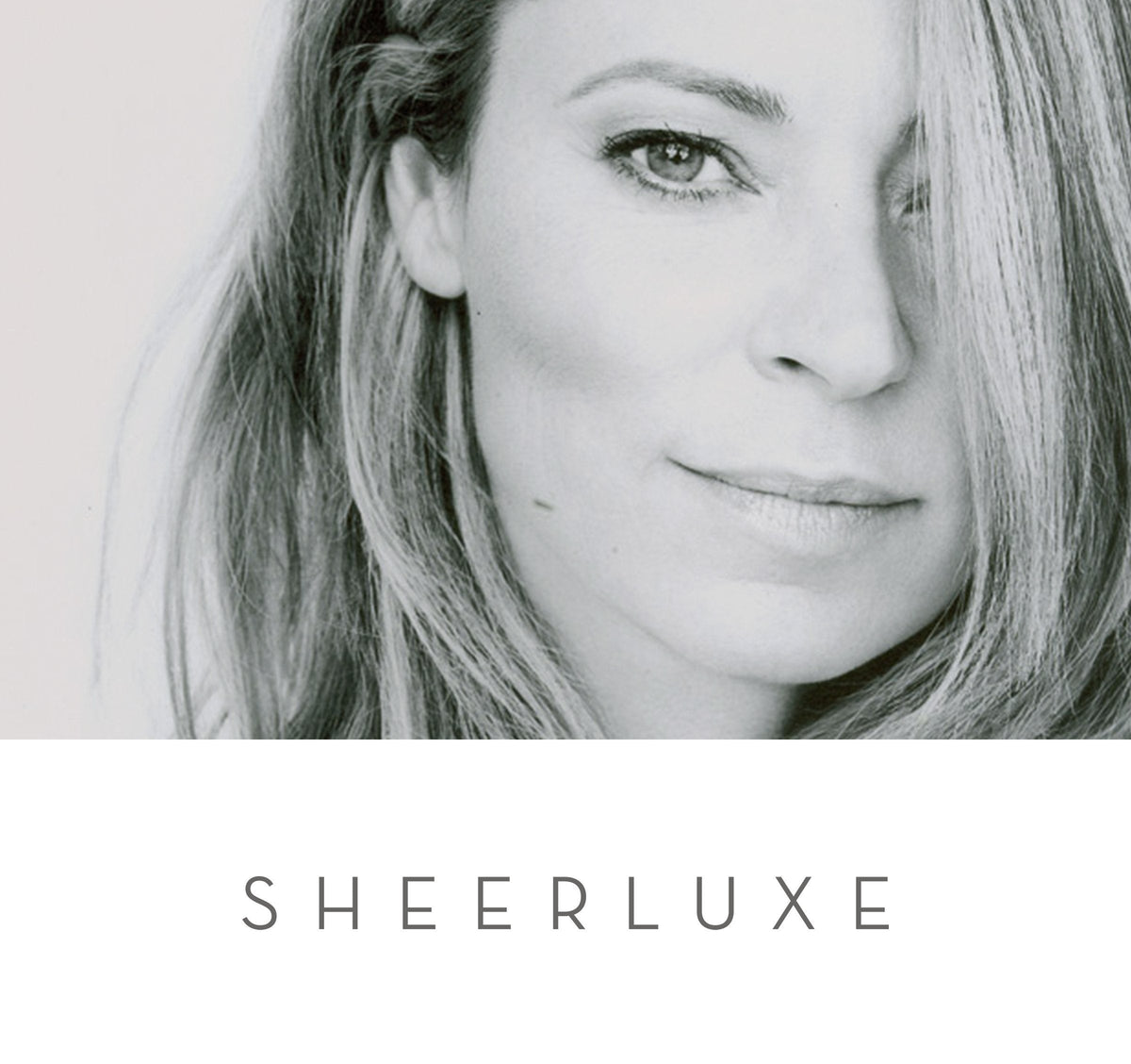 Tight black-and-white portrait of a woman with light hair partly covering the right side of her face, 'SHEERLUXE' below.