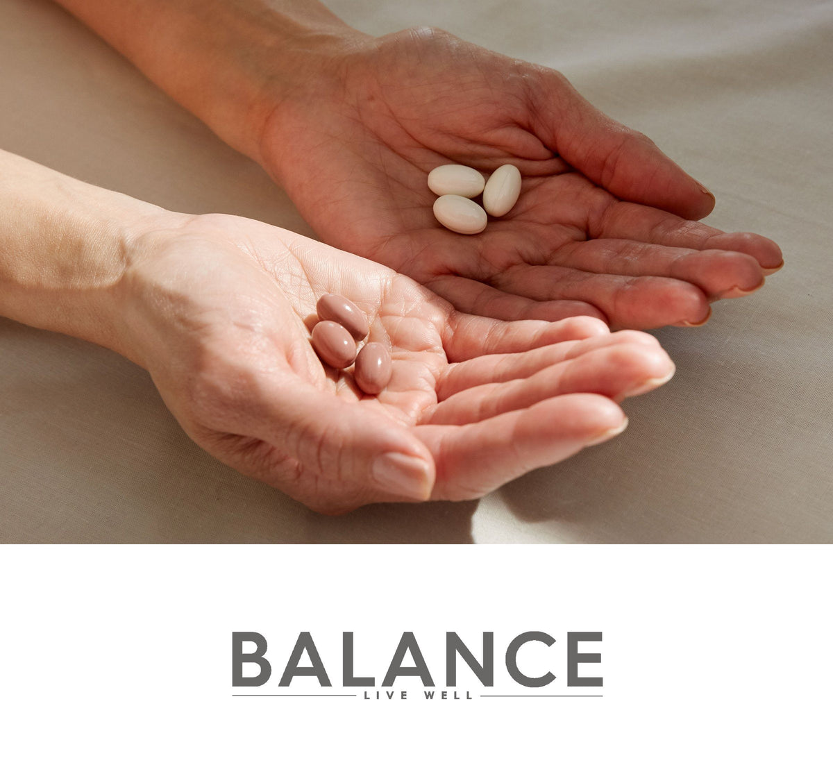 Hands hold three white and three pinkish-beige oval pills over printed BALANCE with LIVE WELL beneath.