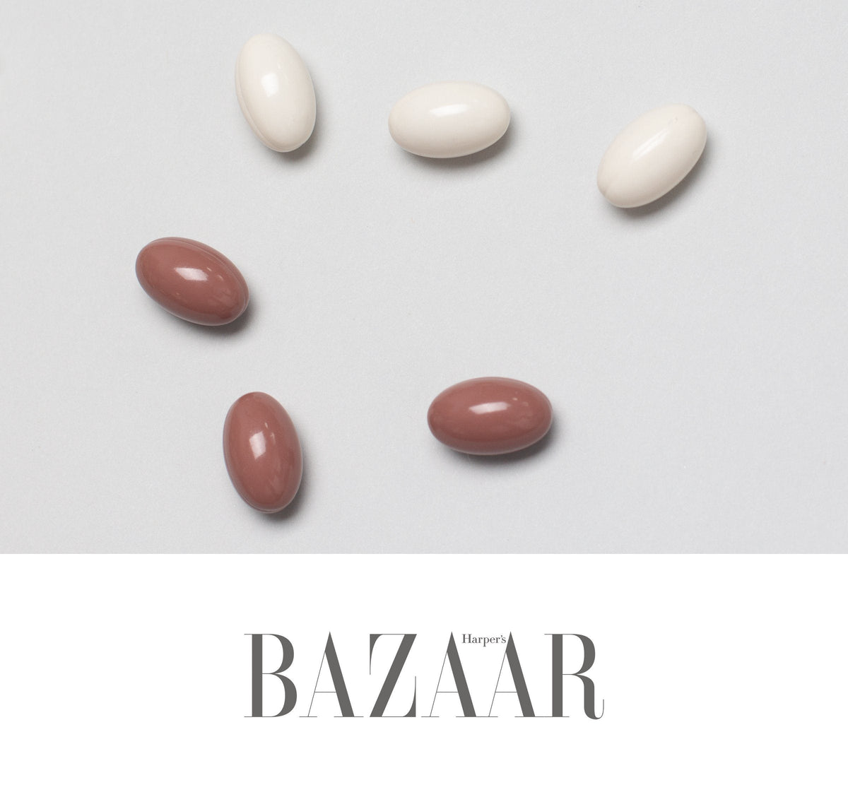 Overhead of six glossy capsules—three white, three muted brown-red—arranged above Harper's BAZAAR text on gray