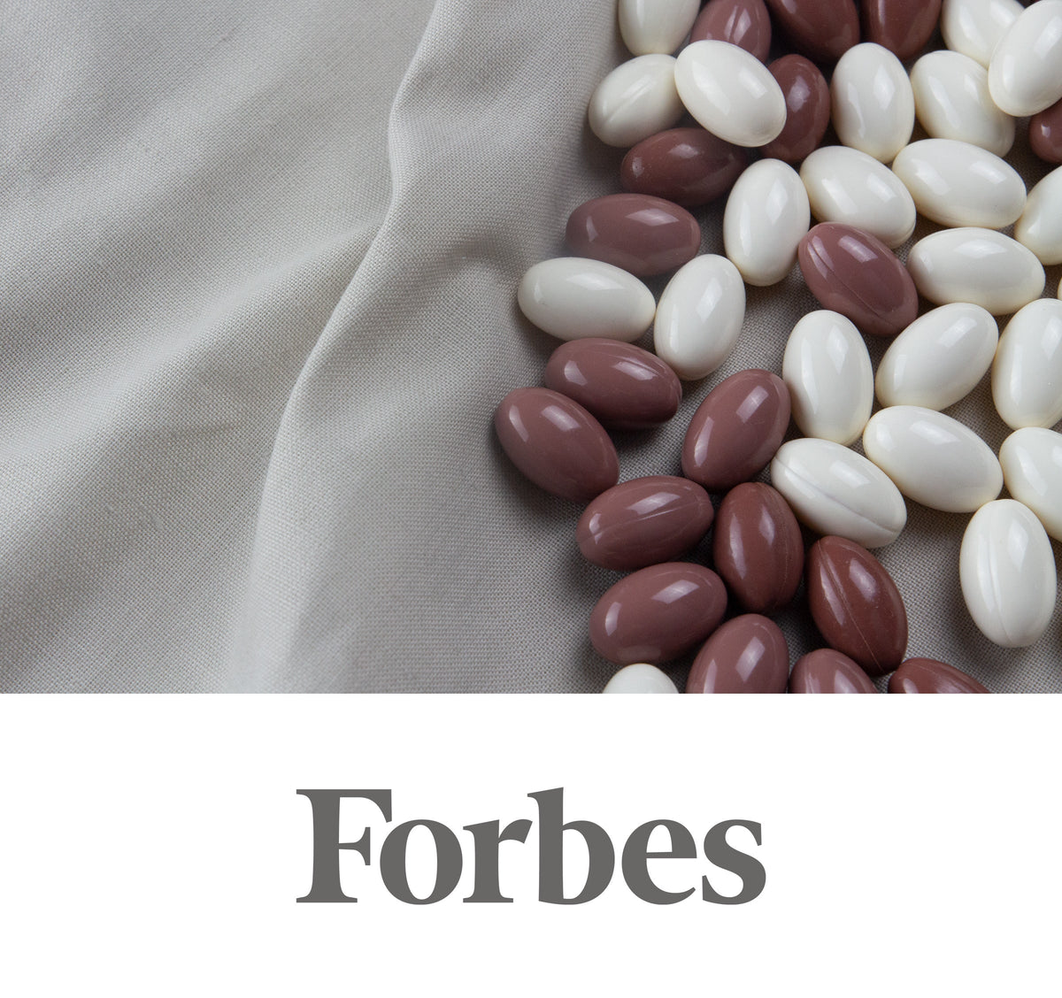 Top-down close-up of white and muted brown-purple oval supplement capsules curved on beige fabric; Forbes logo.