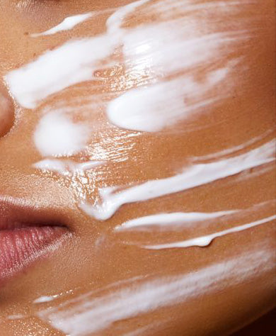 Close-up of a medium-brown face with thick white facial cream streaked across cheek, lower nose and upper lip.