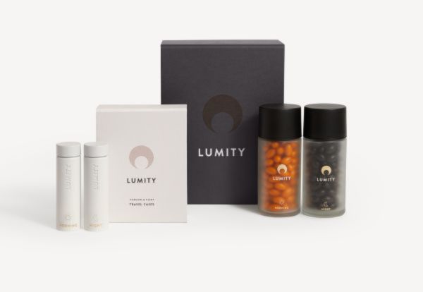 Lumity supplement kit with black box, white travel case, two clear jars of orange and dark brown capsules, eye-level view