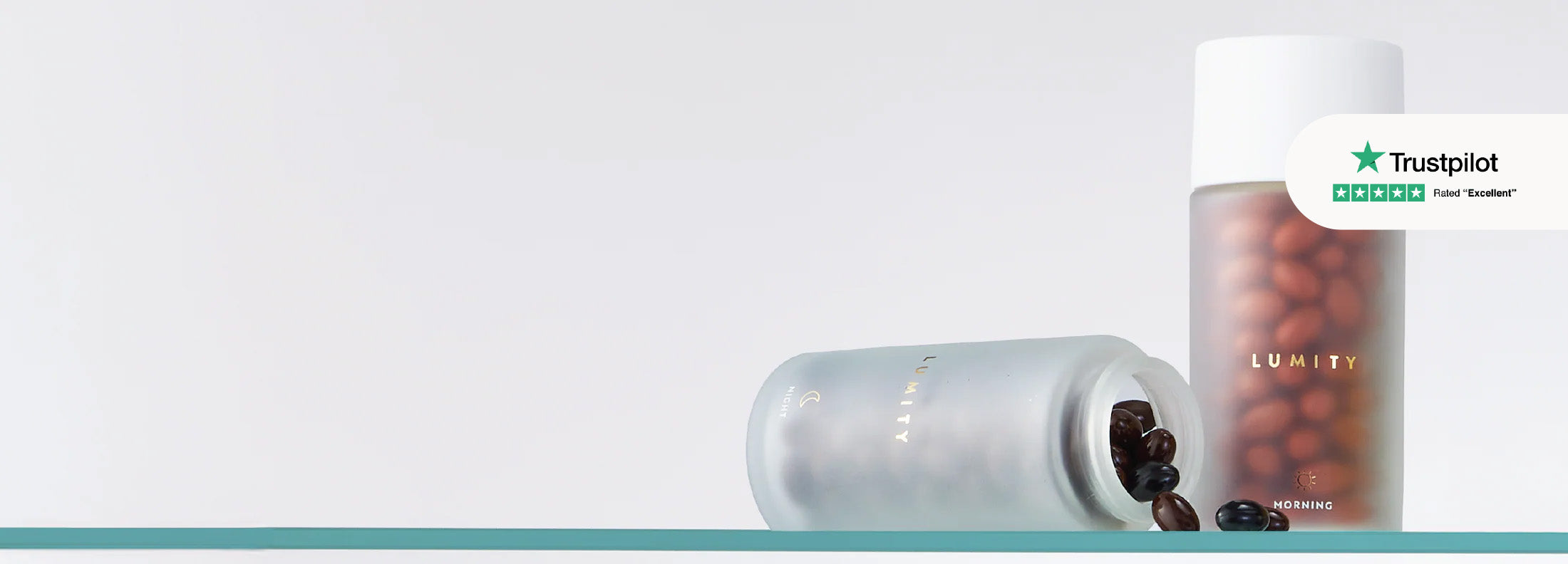 Two translucent bottles with dark softgel supplements, one upright and one tipped over, on a clear surface against a white background