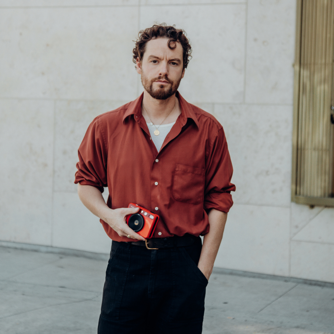 Photographer Jonathan Daniel Pryce standing on street, holding camera