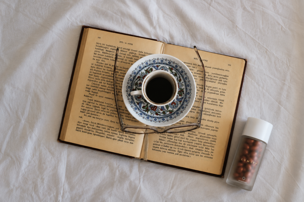 Open book with a cup of coffee and decorative elements on a white surface next to a Lumity Morning supplement bottle