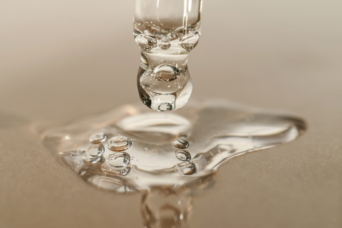 Close-up of a dripping water droplet on a reflective surface.