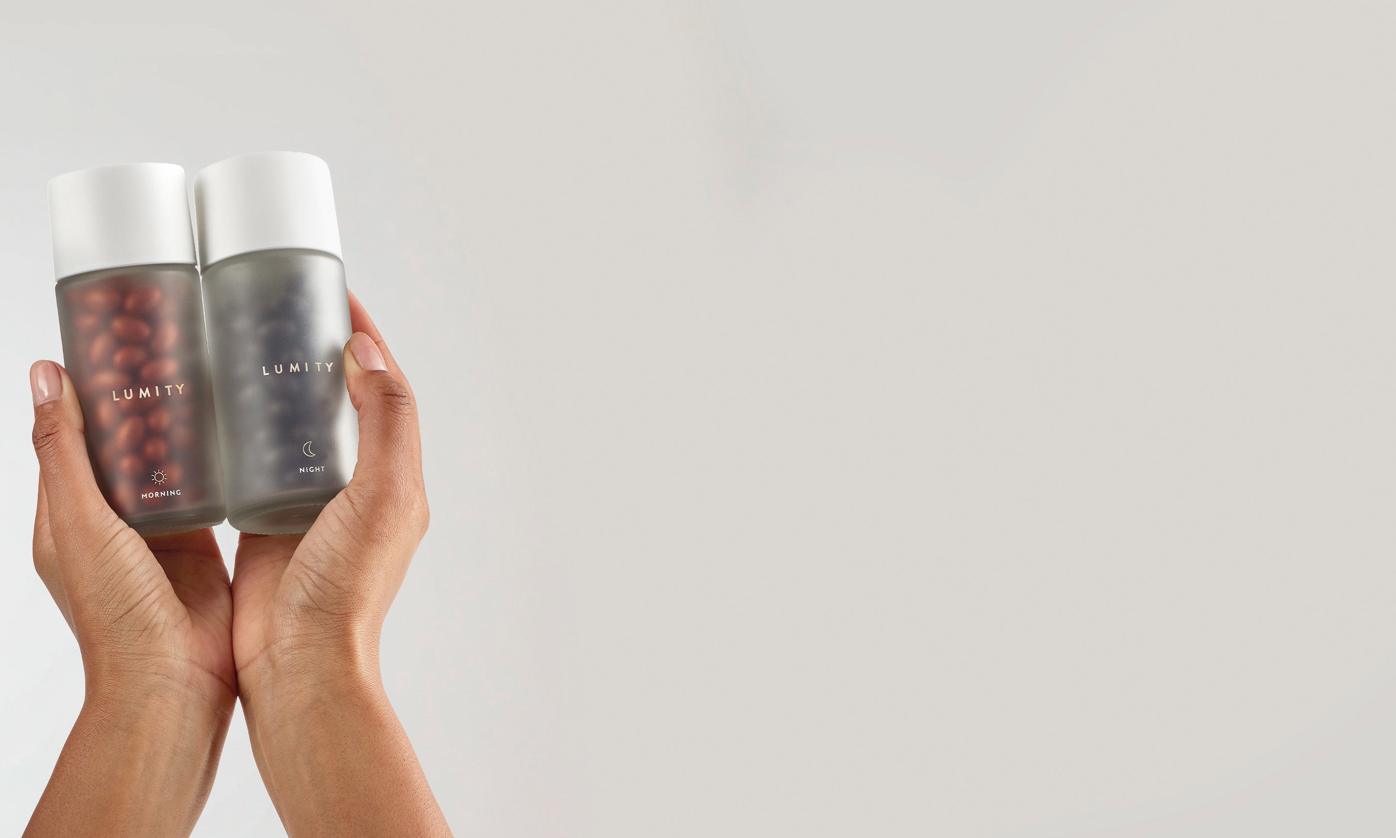 Hands holding Lumity Morning & Night for Women on a plain background