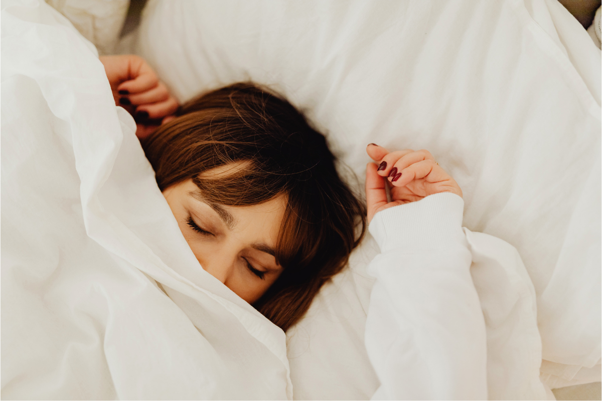 Woman sleeping in bed under sheet